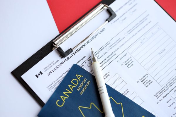 Application for permanent resident card on table with pen and canadian passport close up